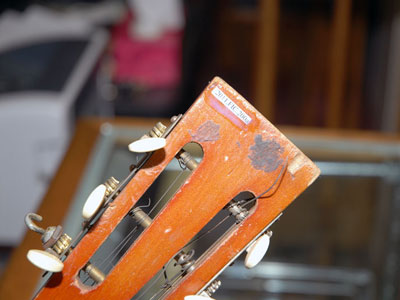 A close-up of a guitar with accession number on the wood handle.