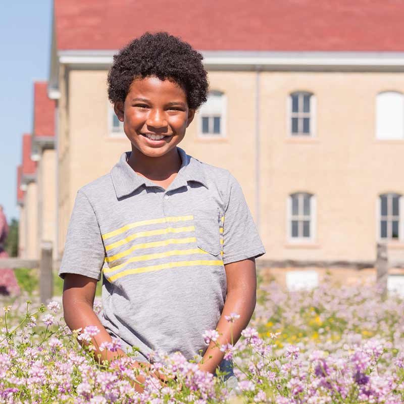Boy standing in a field of wild flowers.