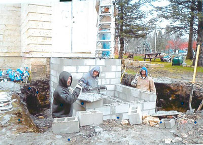 Three workers laying concrete blocks