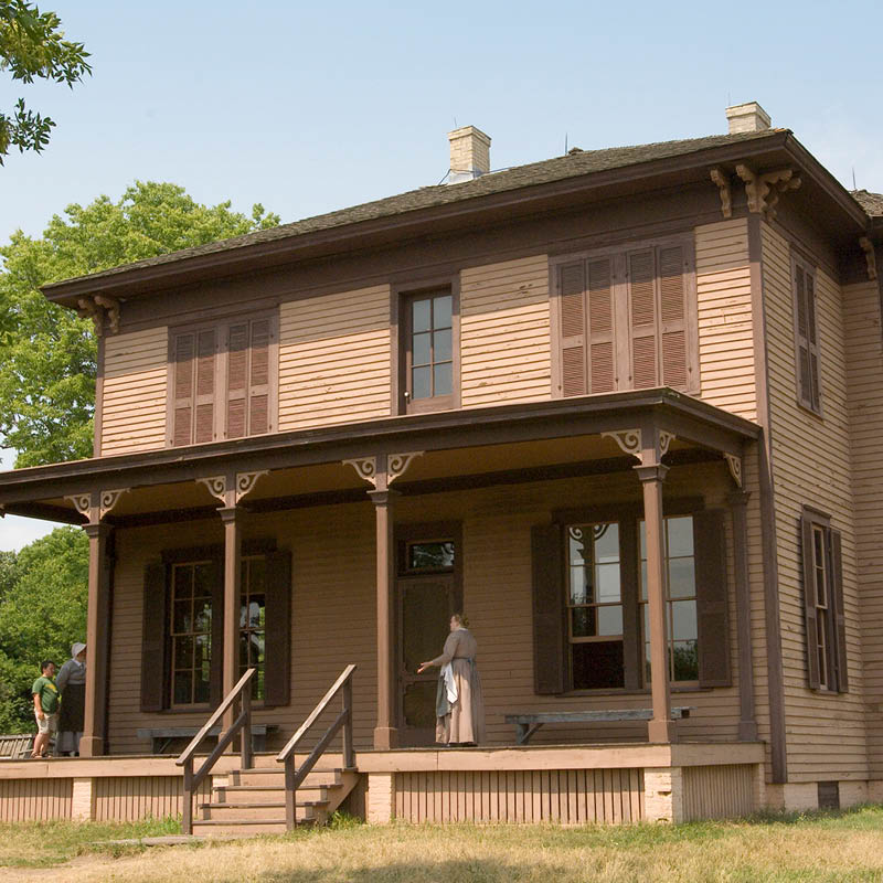Two-story brown house with a porch supported by columns
