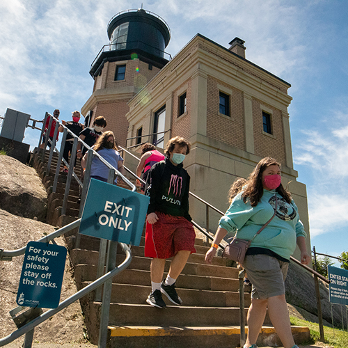 People wearing masks exit Split Rock Lighthouse.