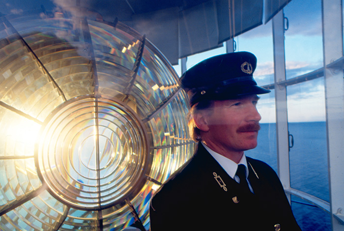 Lightkeeper in front of a lighthouse lens.