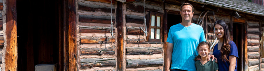 A family standing in front of a log cabin.
