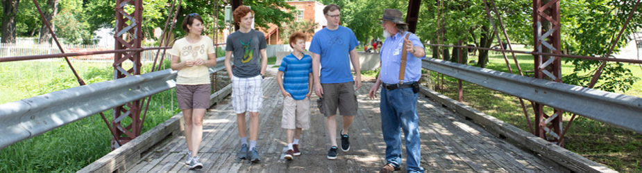 A man leads a group across an old bridge.