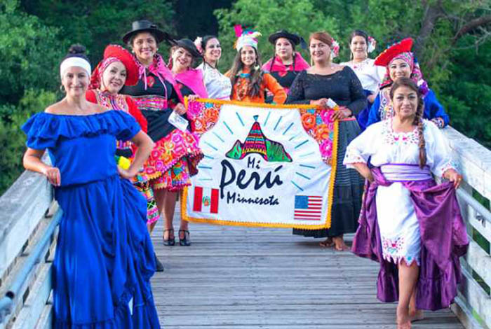 Mi Perú-Minnesota members model a diverse range of traditional Peruvian dance attires while holding a banner with the group's logo.