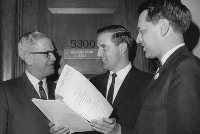 Minnesota Farmers' Union president Ed Christianson, Senator Walter Mondale and Dr. Blue Carstenson of the National Farmers' Union stand together looking over papers.