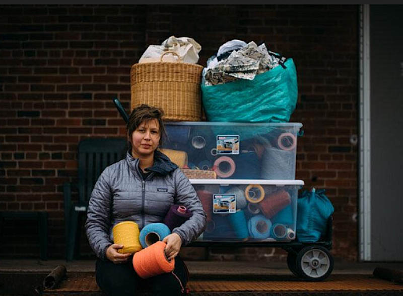 Woman holding large spools of thread.