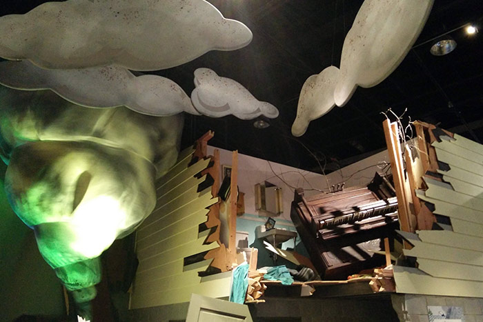 Museum display of a fabric tornado and damaged living room.