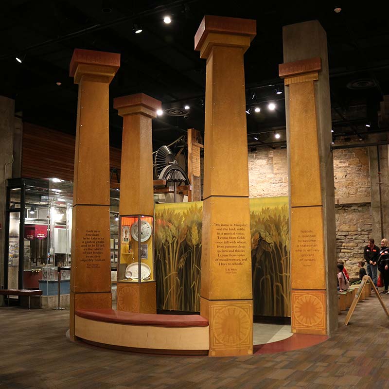 Wheat emporium sculpture with four large columns inscribed with text.