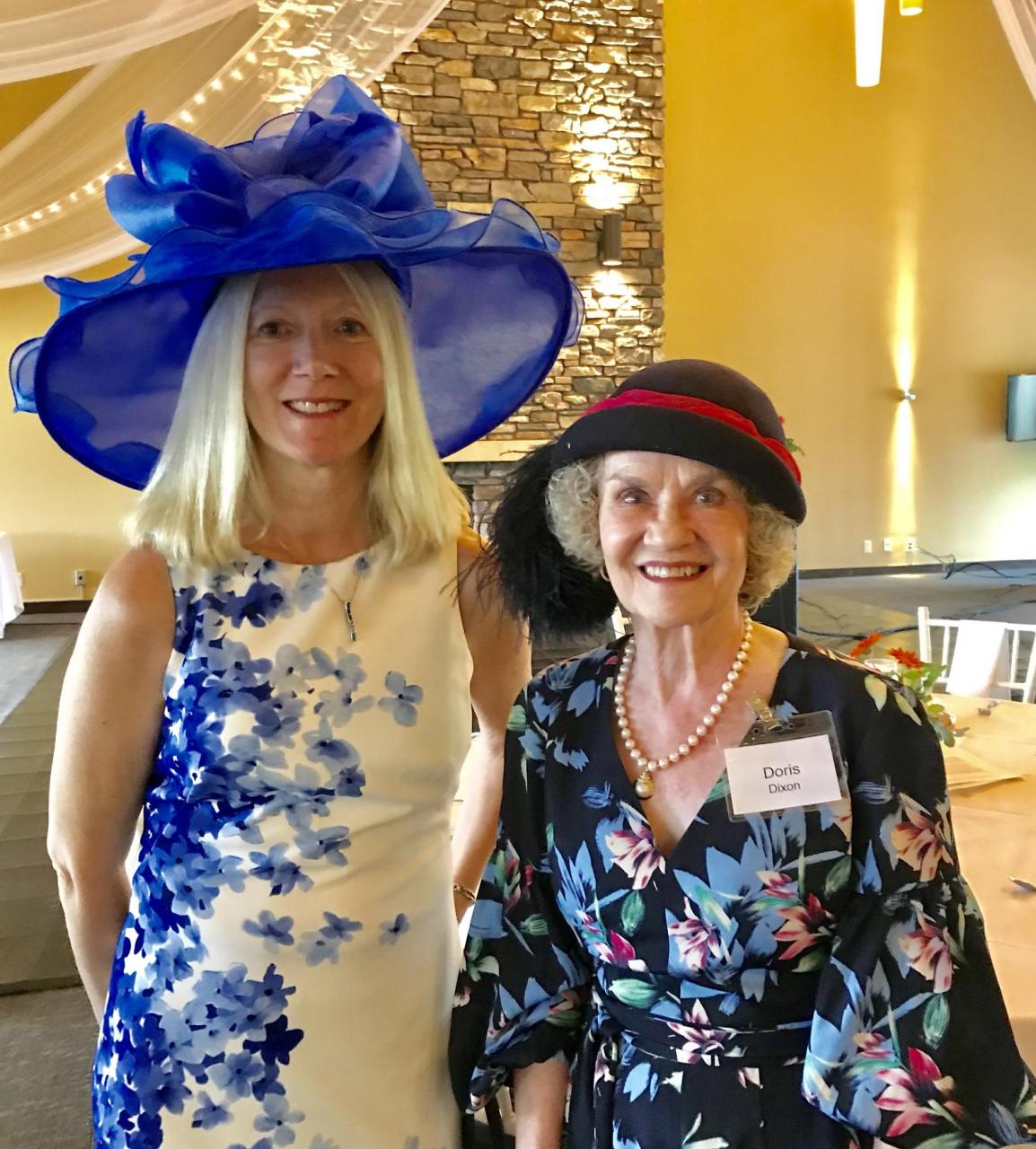 Two women wearing fancy hats.