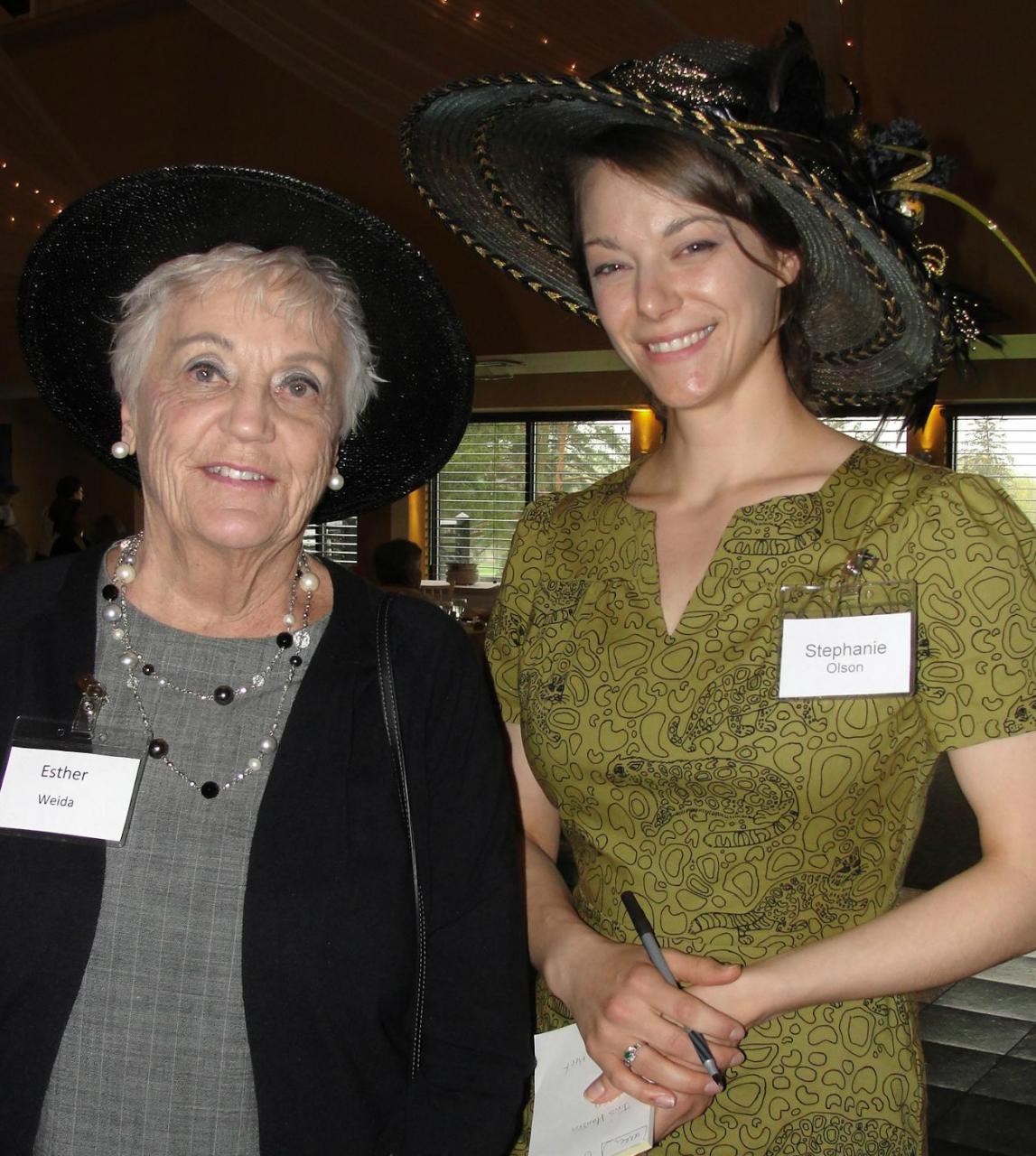 Two women wearing fancy hats.