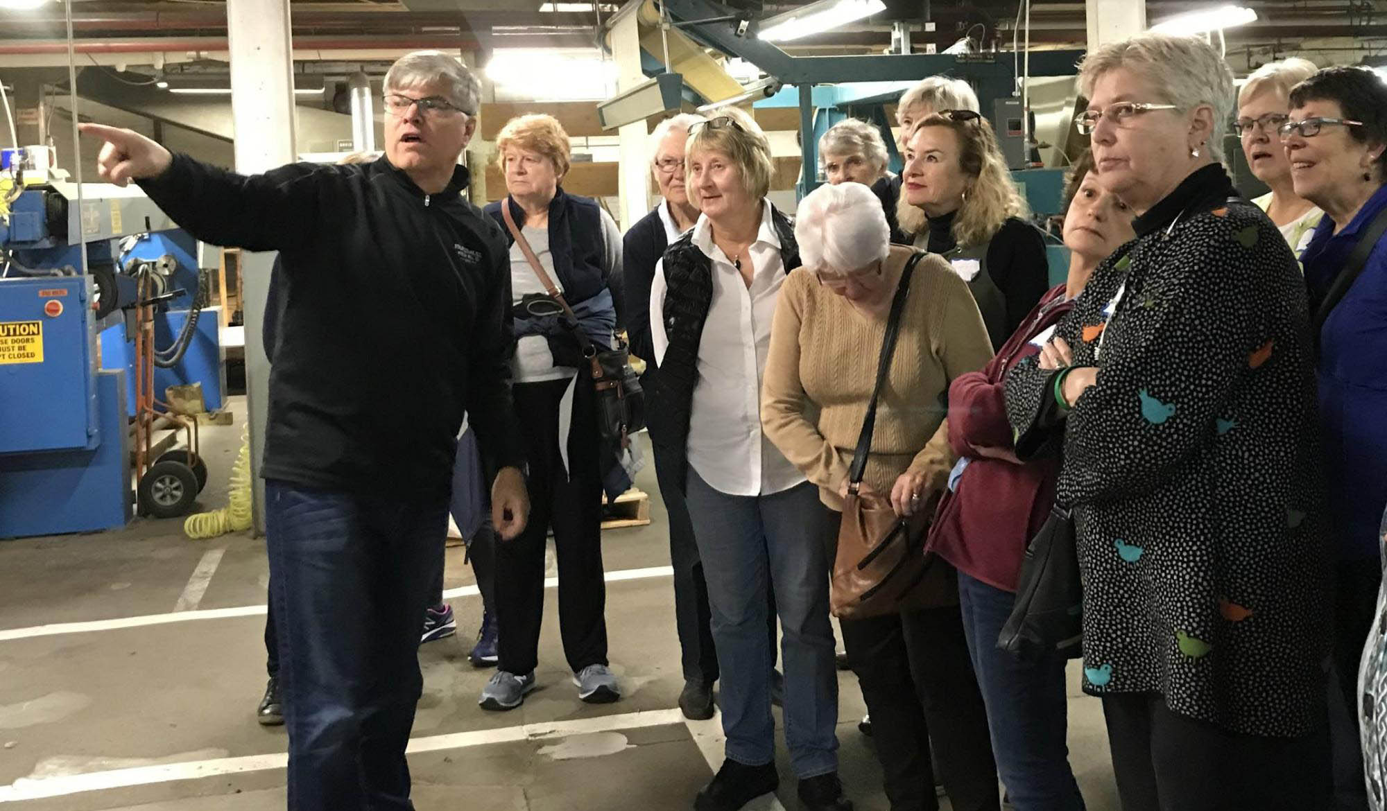A man points as he leads a group of women on a tour.