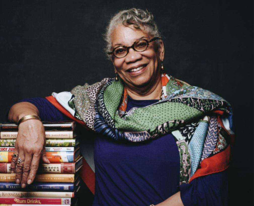 Woman standing with arm on books.