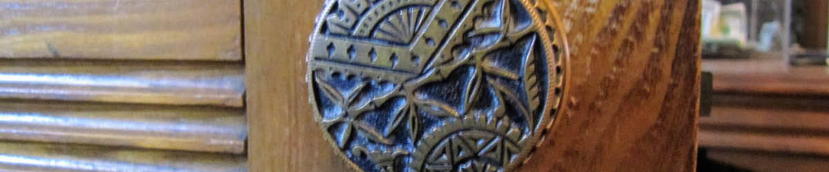 A close-up of a door knob with engraving of a fan, bamboo, and a wheel.
