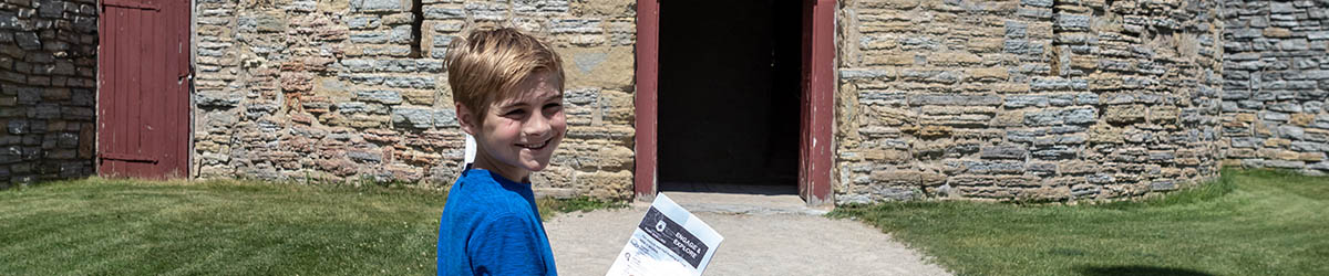 A boy in a blue t-shirt smiling during field trip at Historic Fort Snelling.