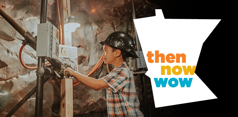 A boy in a hard hat pretends to drill in the mining area of the Then Now Wow exhibit.