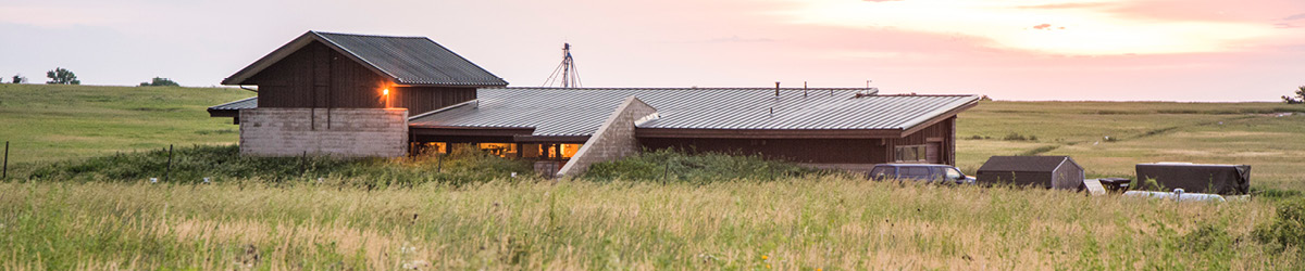 View of Jeffers Petroglyphs visitor center sitting in the middle of prairie land with the sun setting in the background.