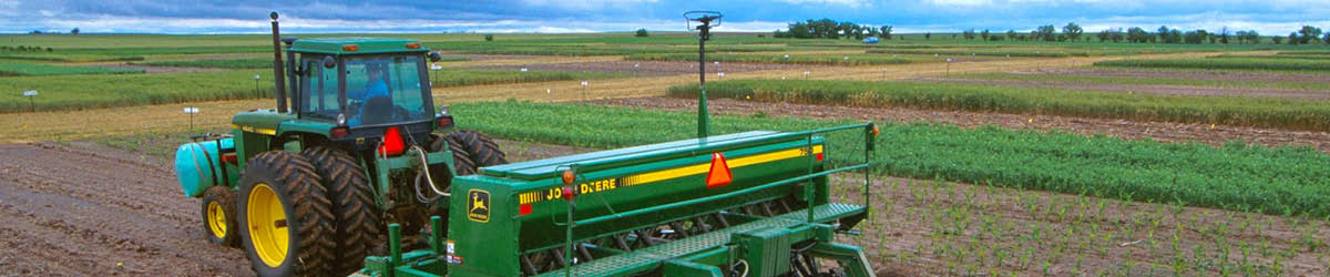 John Deere tractor with planter in a dirt field