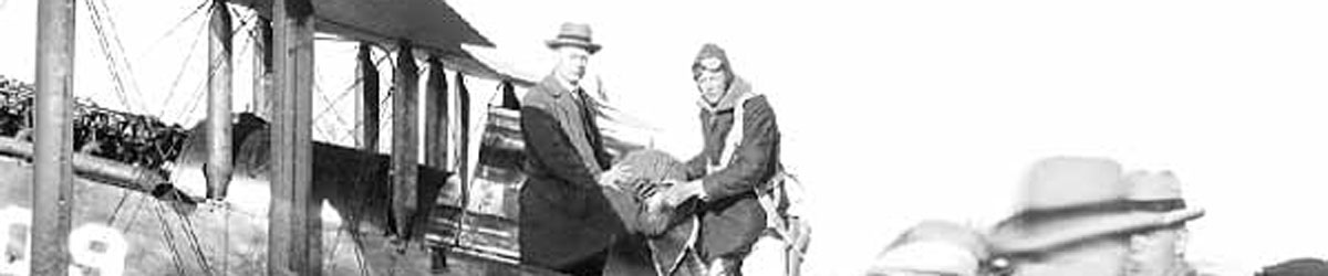 Two people carrying a bag of mail off from an airplane.