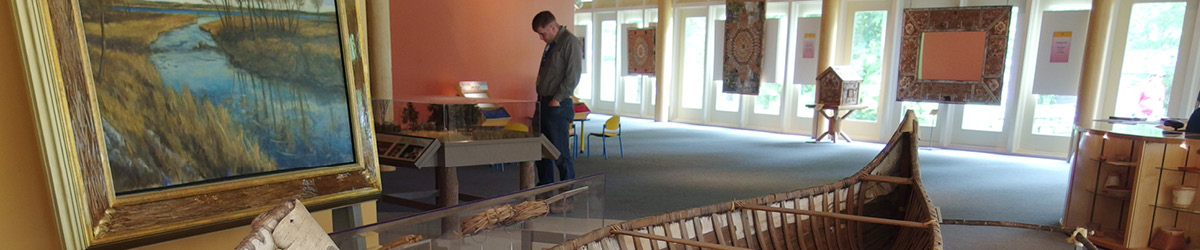 Museum interior showing a canoe, painting, and other exhibits.