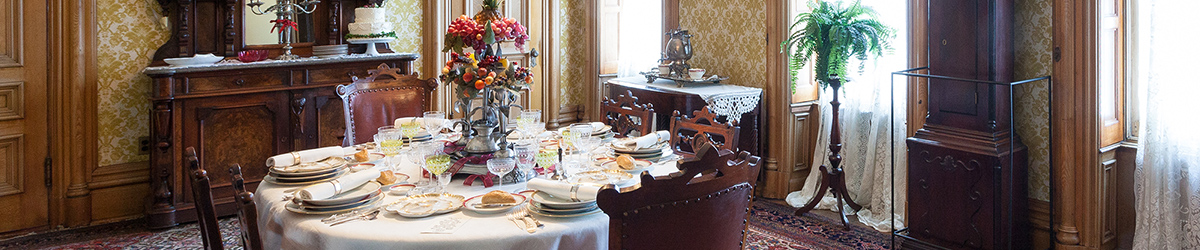 Six settings of antique dishes on dining table with flower centerpiece