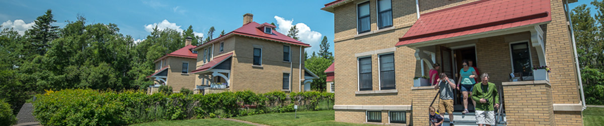 People walking out of a square, light-brown building, with two similar buildings in the background