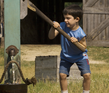 Young boy pulling water well on Oliver Kelley Farm