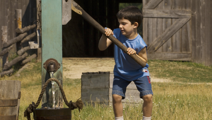 Young boy pulling water well on Oliver Kelley Farm